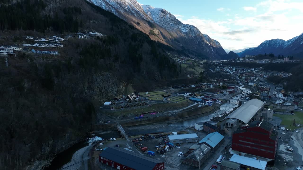 Aerial approaching Lothepus Camping in Odda Norway over the river. Wide view of valley and surrounding industrial area.