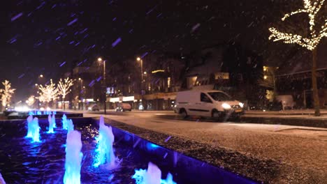 snowy night in city with illuminated fountains