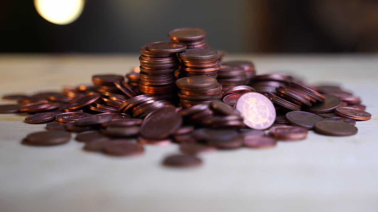 las monedas de céntimo de acero alemanas yacen en una gran pila en palos individuales sobre una mesa de madera y giran