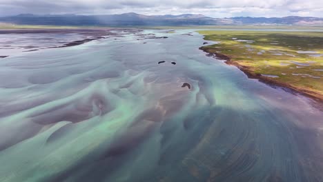 textured braids form in the olfuse river in iceland as the glacial mountain water flows towards the ocean in southern iceland on a beautiful summer day in the land of fire and ice
