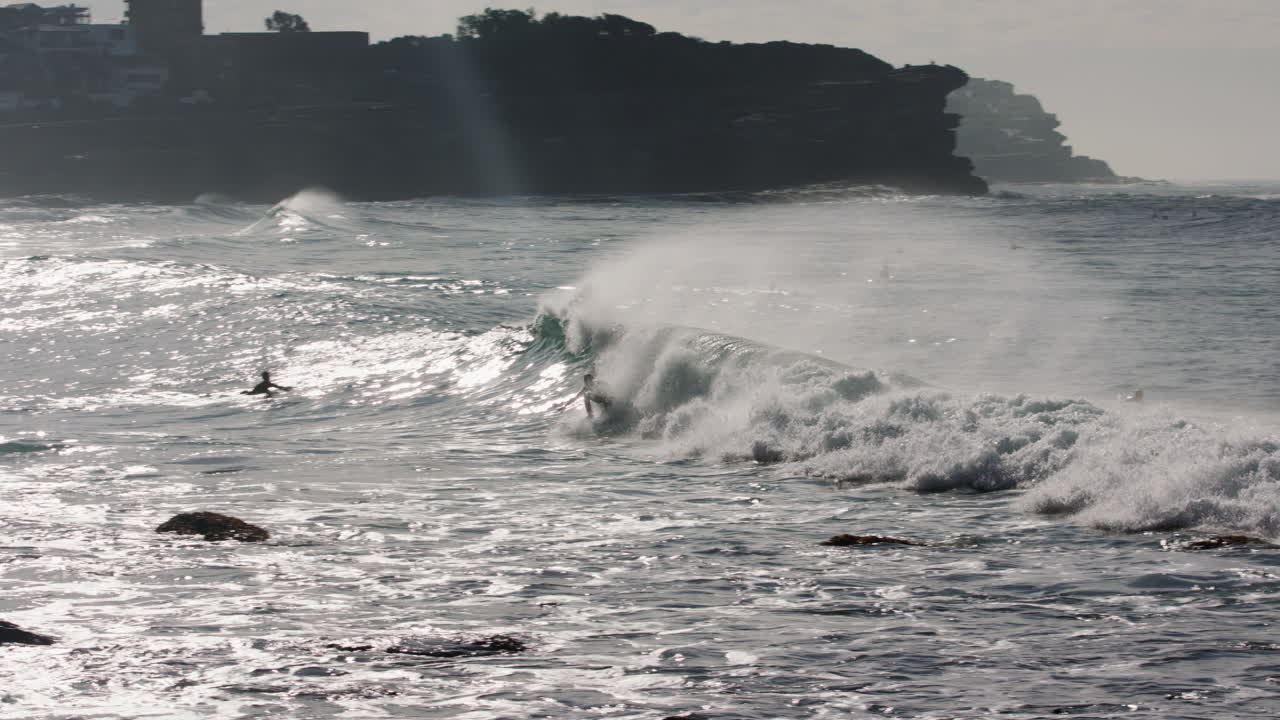 서퍼는 골든 아워 동안 암초의 얕은 부분 근처에서 거친 화이트워시 파도를 탄다