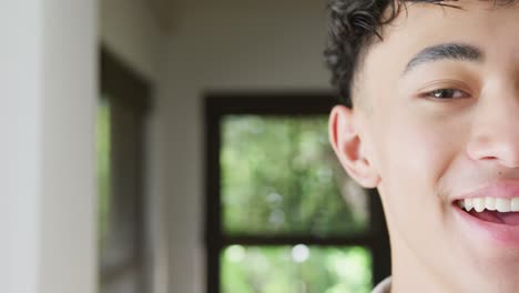 Portrait-of-happy-biracial-male-teenage-boy-at-home,-slow-motion