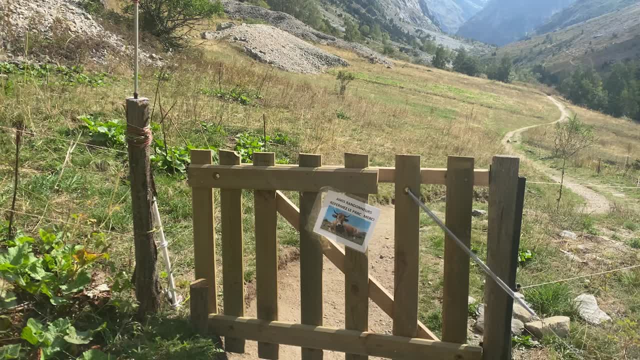 Magnifica carrellata ampia di un cancello che si apre su un sentiero sterrato nelle Alpi francesi