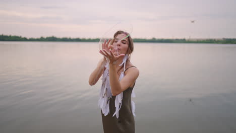 a young female artist shows a soap bubble show by blowing up large soap bubbles with her hands in slow motion