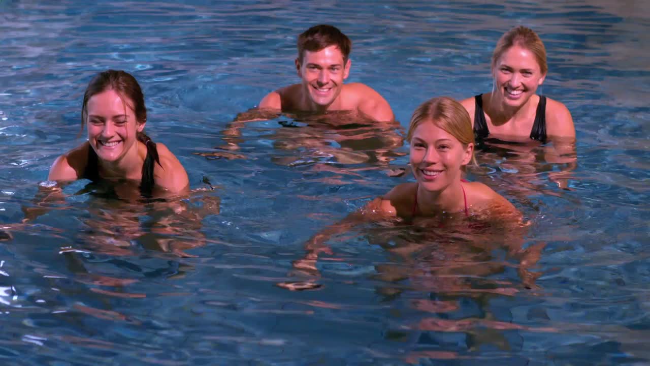 피트니스 수업 은 수영장 에서 카메라 에 미소 짓는 수영 에어로빅 을 하고 있다