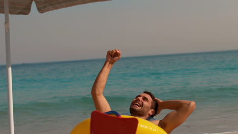 hombre feliz usando aletas y levantando el puño en la playa