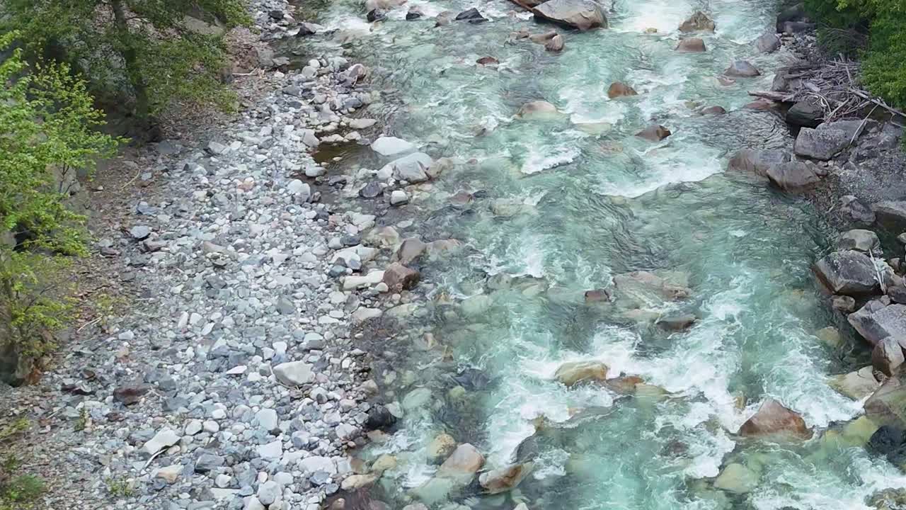 Drone rises smoothly, the turquoise waters of the glacier-fed river stretch below, cutting through rugged mountain terrain