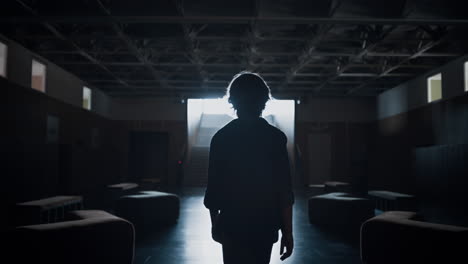 Schoolboy-silhouette-walking-dark-corridor-alone.-Upset-teenager-going-hall.