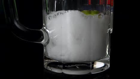 close up shot of soda which get filled in a glas with lime and ice cubes in slow motion