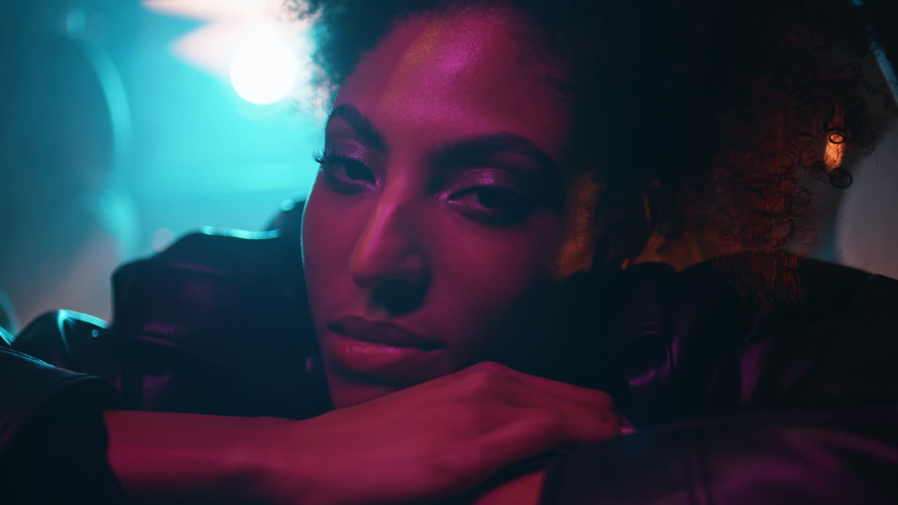 Bright girl sitting auto under mysterious neon lights closeup. woman