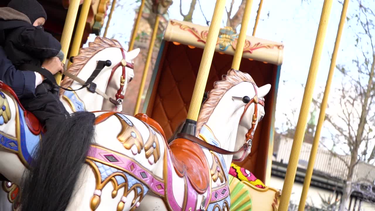 Young child rides colorful old-fashion carousel horse, Tivoli Gardens, Copenhagen, Denmark, close up slow motion pan