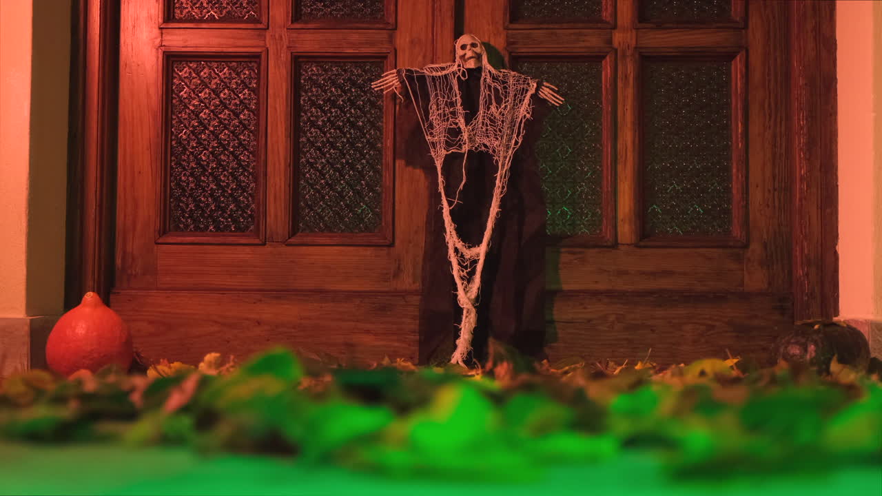 decoración de la puerta de la casa de halloween con follaje otoñal movido por el viento