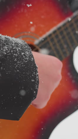 primer plano de manos tocando la guitarra con tonos rojos y naranjas vibrantes, la manga cubierta de nieve visible, creando una mezcla armoniosa de música y el frío del invierno