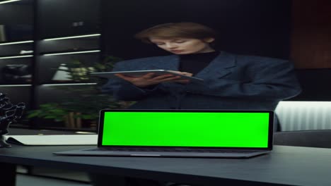 mujer trabajando en tableta y portátil en una oficina moderna