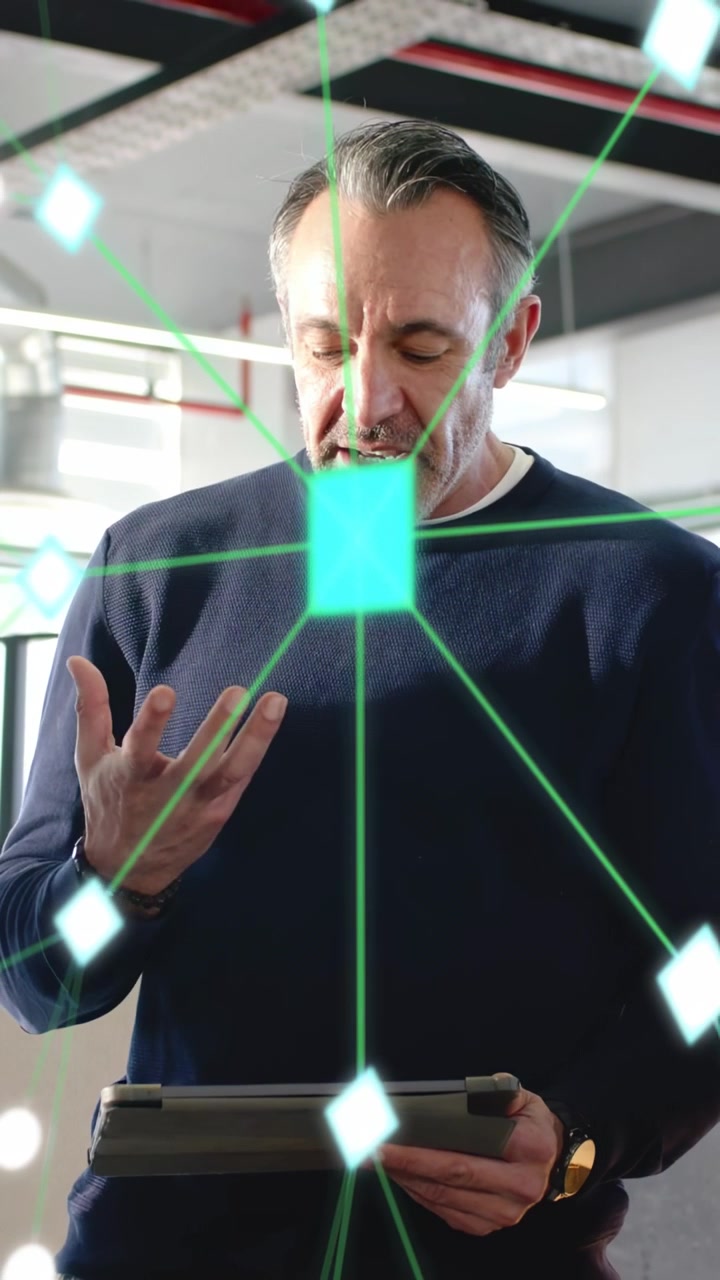Vertical video: Man holding tablet, gesturing as green square expanding into hologram for tech demo