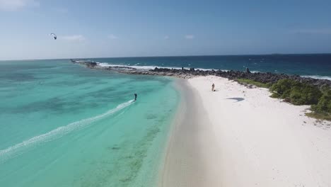 Man-kitesurf-on-azure-sea-along-shore-beach-Crasqui-island,-Los-Roques