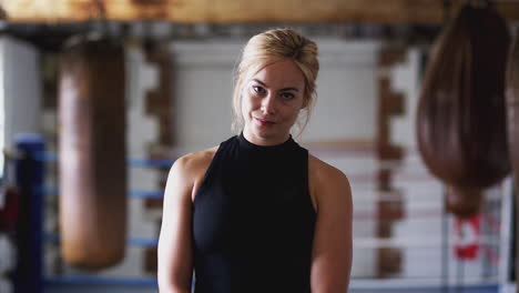 Portrait-Of-Female-Boxer-In-Gym-Training-With-Old-Fashioned-Punching-Bags