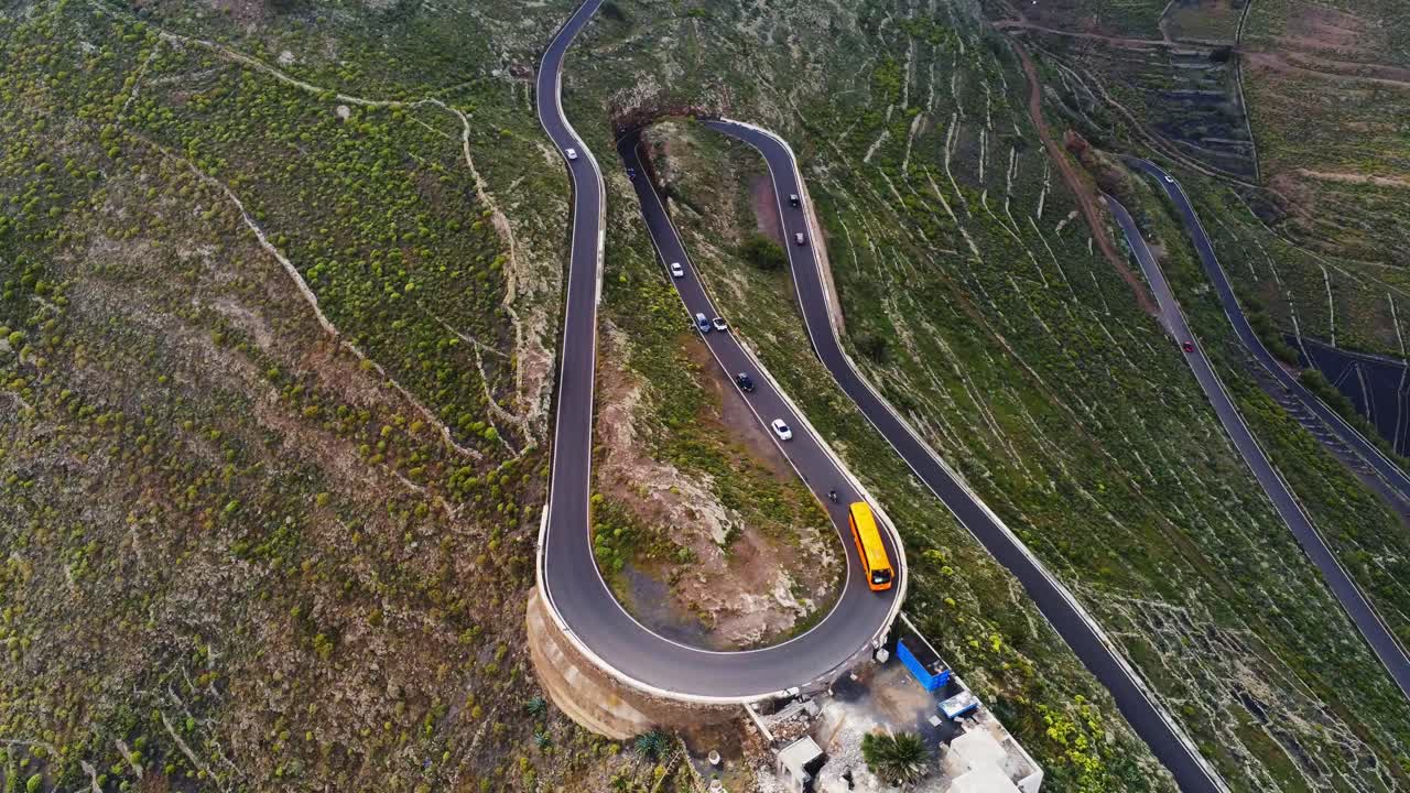 sinuosa carretera de montaña en la isla de lanzarote con muchos coches y autobús amarillo, vista aérea