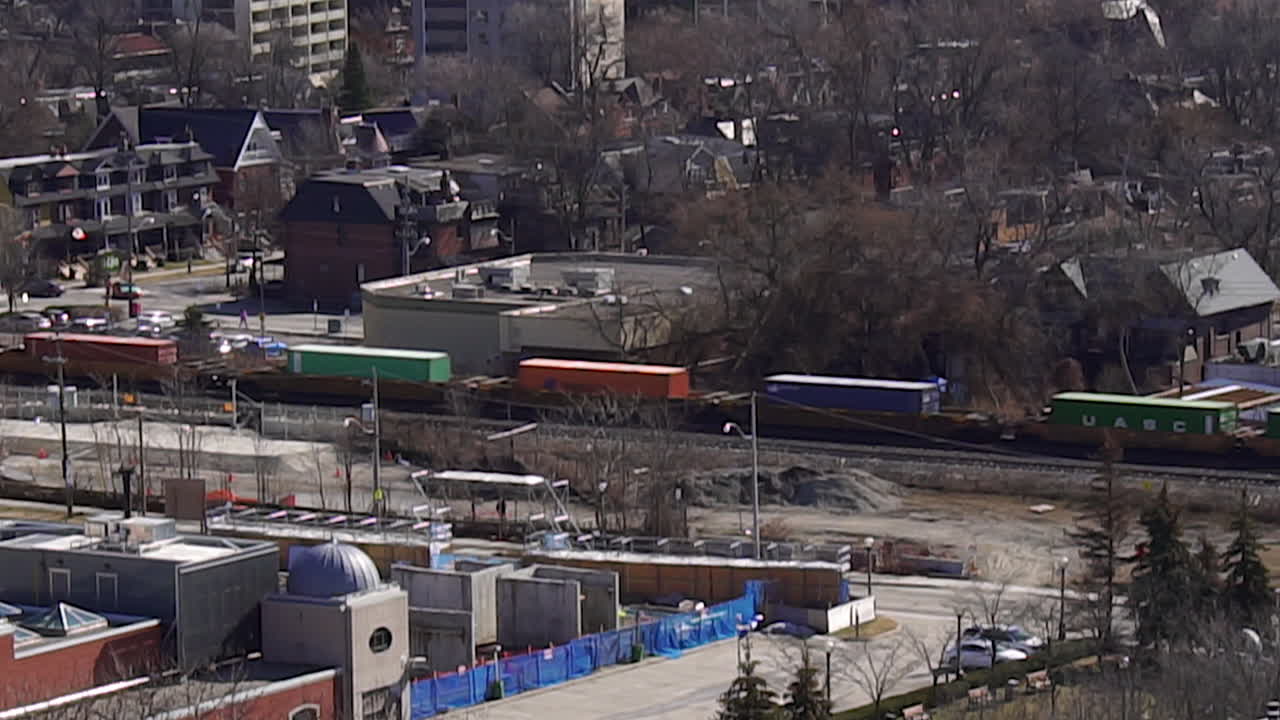 широкий снимок грузового поезда, проходящего через неприметный город в дневное утро