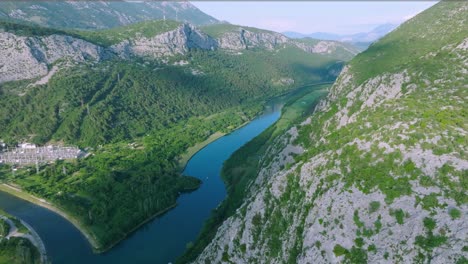 wide aerial pan of cetina river and green mountains in rural croatia