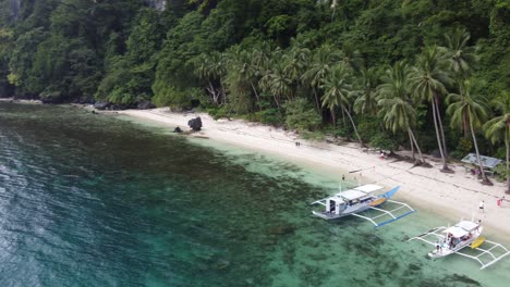 aerial trucking pan across double outrigger canoes beached on pasandigan cove