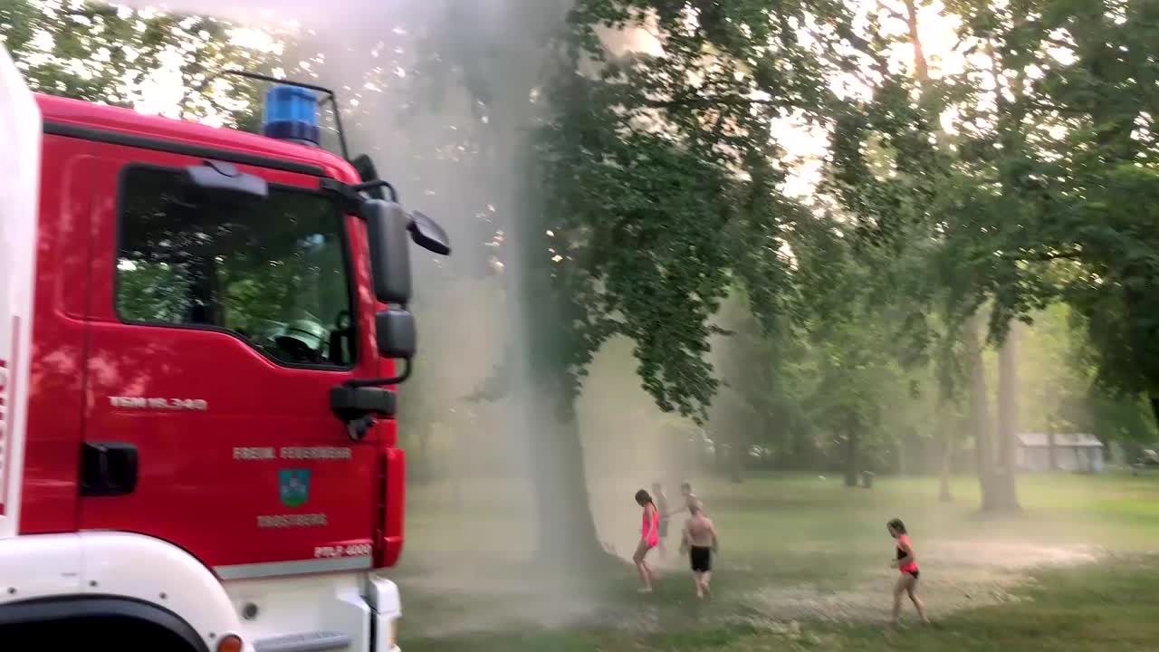 camión de bomberos alemán rociando agua para niños y árboles en un caluroso día de verano-11