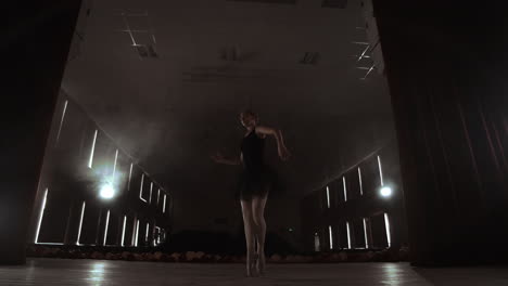 slow motion: the prima ballerina in a black dress performs rotations and graceful dance moves. the camera moves on gimbal