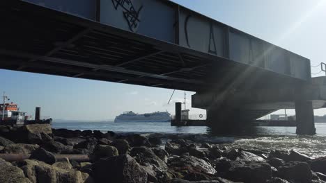 view looking underneath pier with cruise ship going past in distance on river tagus in lisbon