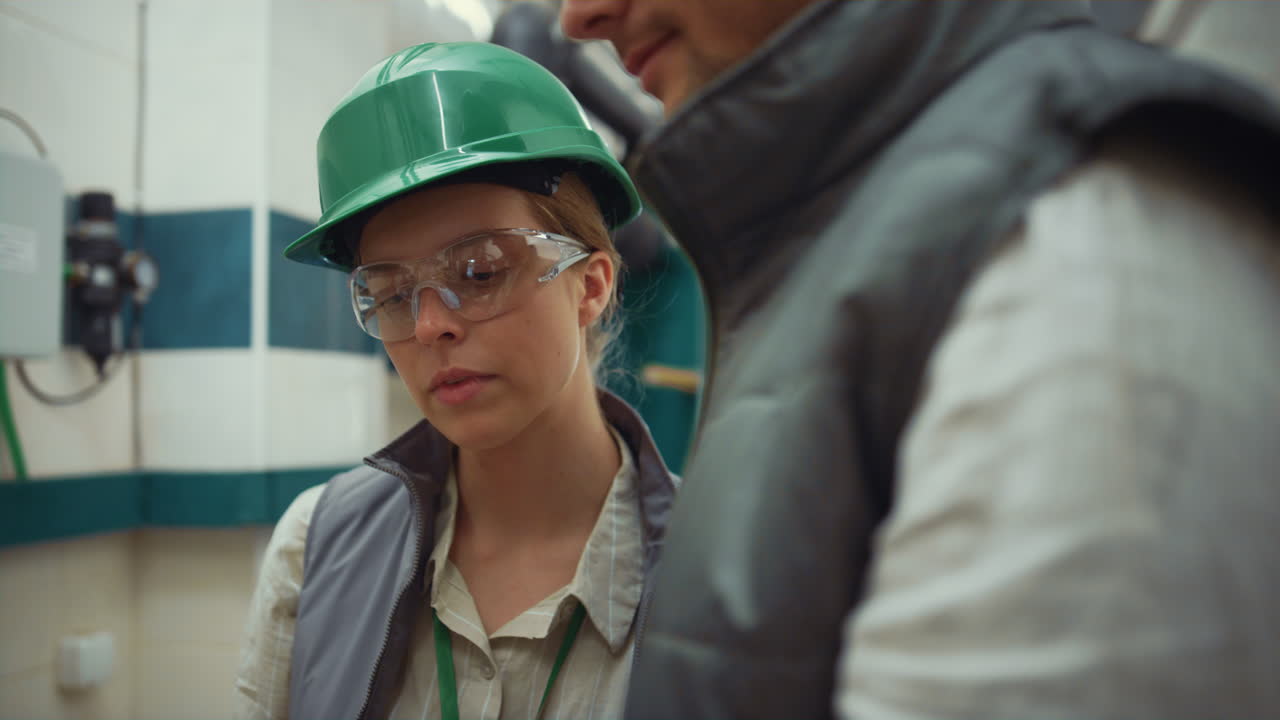 женщина-наблюдатель говорит с коллегой на современном производственном объекте вблизи.