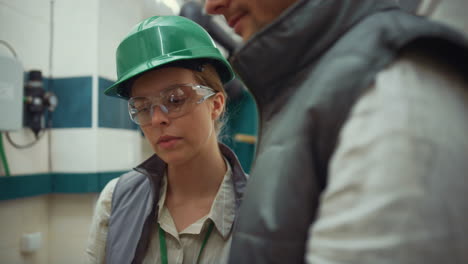 woman supervisor talking colleague at modern manufacture facility close up.