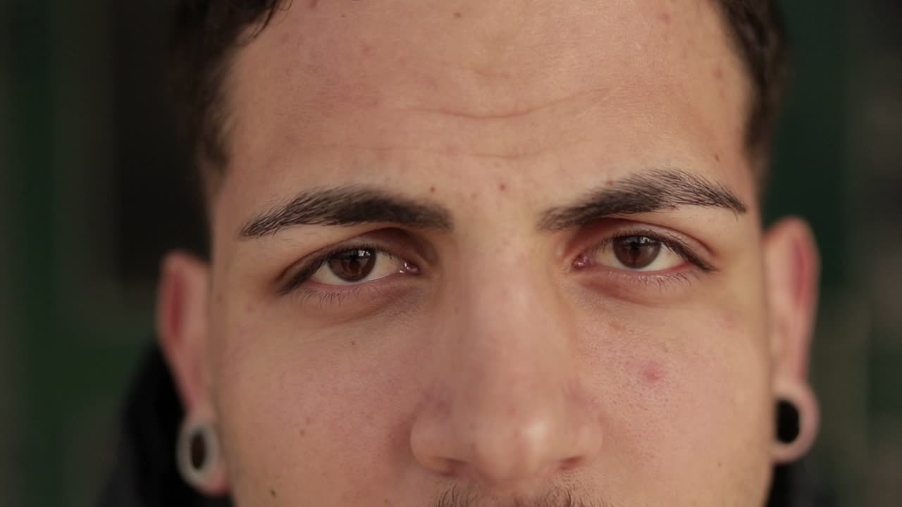 disparo de cerca de un joven guapo con ojos marrones mirando a la cámara