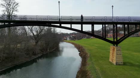 Flying-under-the-iconic-Grant-Park-Pedestrian-Bridge-with-the-historic-township-of-Galena,-Illinois-on-the-right