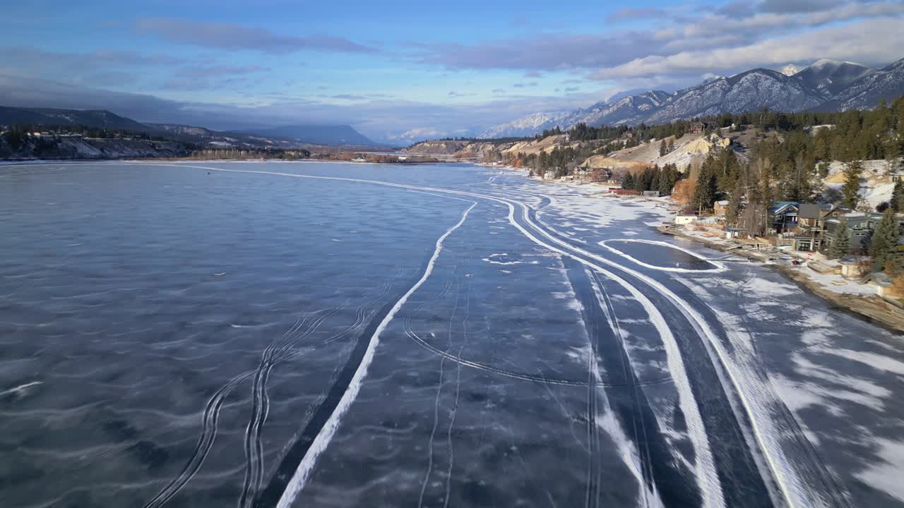 вид сверху с беспилотного летательного аппарата на замерзшее озеро уиндермир, проходящее вдоль юго-восточного берега, с конькобежцами и искусственными катками, сделанными на льду внизу