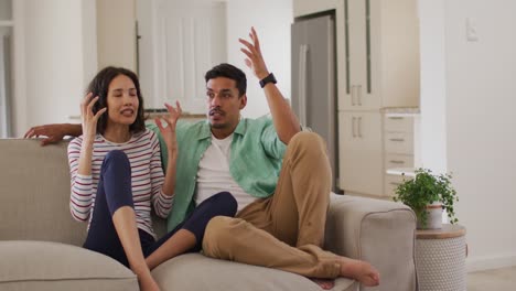 Angry-hispanic-parents-sitting-on-sofa-arguing-looking-at-dancing-daughter