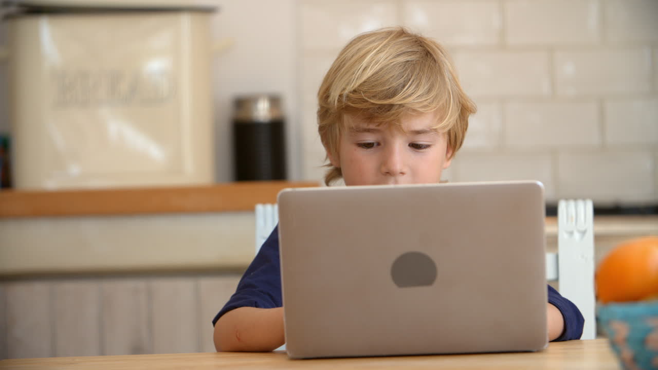 niño usando una computadora portátil en la mesa de la cocina, de cerca