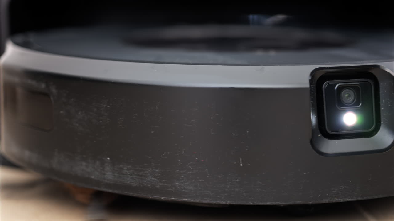 Close up of a black robot vacuum cleaner moving and rotating on the floor tiles