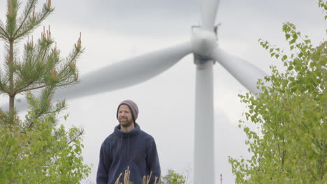 wind power - a bearded man looks at wind turbines on a windy day