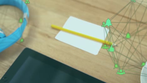 animation of connected icons globes over pencil, paper, headphone and digital tablet on wooden table