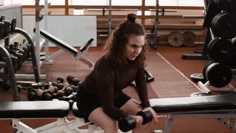 woman doing bicep curls with dumbbells in a gym