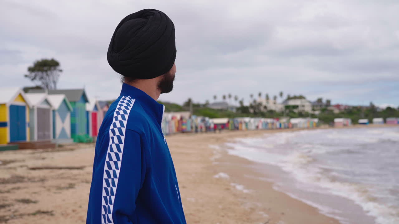 Uomo Sikh indiano che sorride davanti a una riva tranquilla in spiaggia