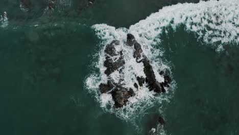 Foamy-Waves-Splashing-On-Ocean-Rocks-At-Puerto-Escondido,-Oaxaca,-Mexico---aerial-top-down