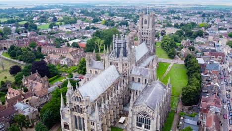 aerial: ely cathedral with urban city residential area in england, drone tracking shot