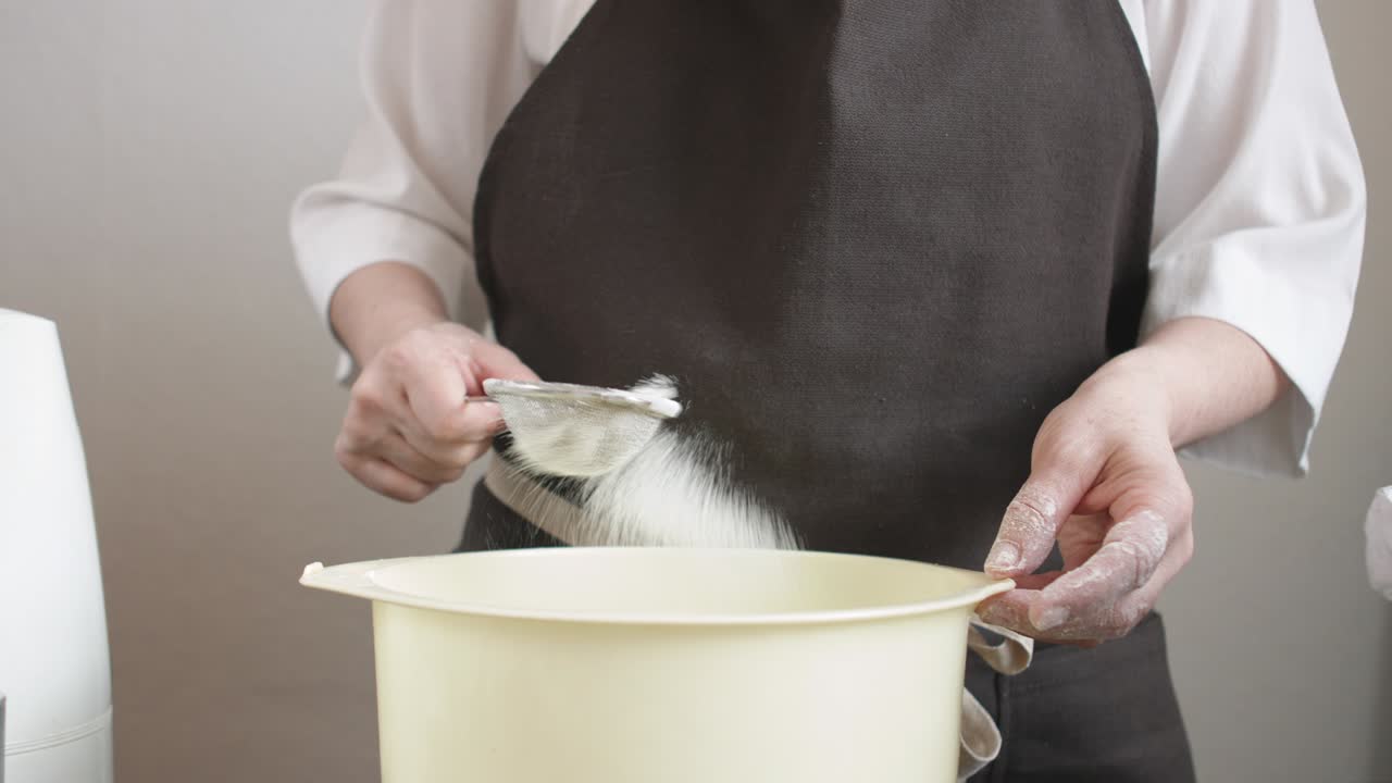 Female hands sifts the flour