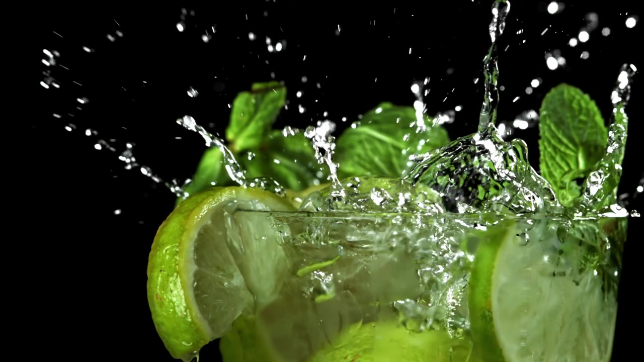Jääpala putoamassa Mojito-cocktailiin limen ja mintun kanssa