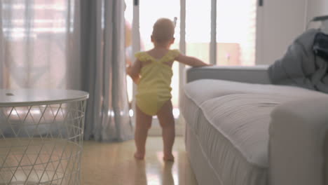 baby girl making her way leaning on the sofa at home