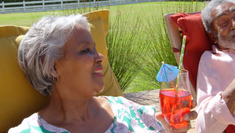 Vista-Frontal-De-Una-Pareja-De-Ancianos-Negros-Relajándose-En-Una-Tumbona-En-La-Piscina-En-El-Patio-Trasero-De-Su-Casa-4k