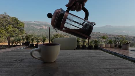 café vertido de prensa francesa con paisaje, montañas, paisaje en el fondo, café negro, café espresso, vacaciones, aire bnb, vacaciones, en el café de jardín