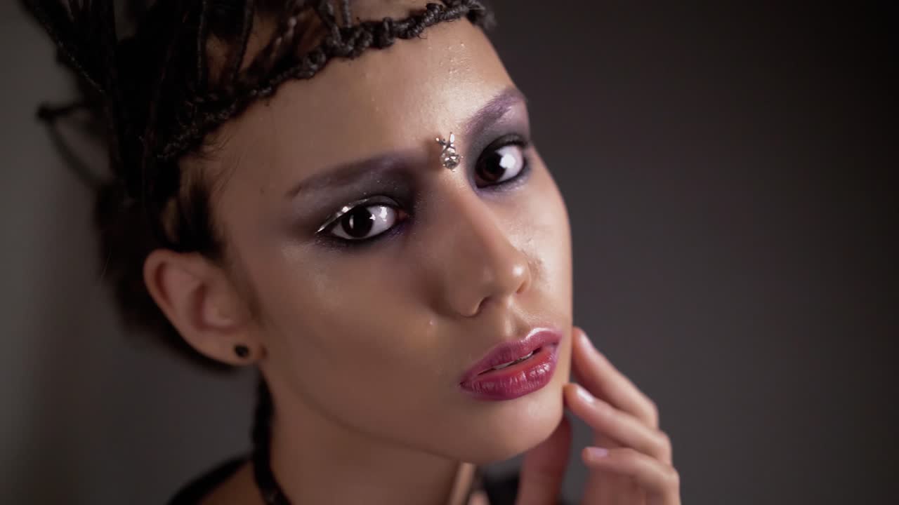 joven hermosa posando frente a la cámara en la cara joyas de metal