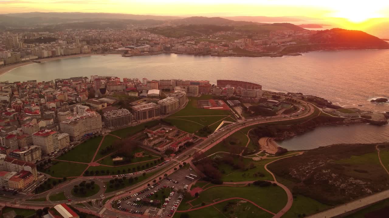 Vista aerea al tramonto de La Coruña, regione della Galizia: un drone sorvola il centro urbano e la spiaggia costiera, rivelando il paesaggio della città