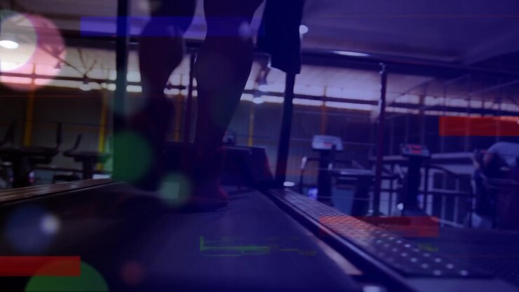 Animation of multicolored lines and lens flares over low section of man running on treadmill in gym
